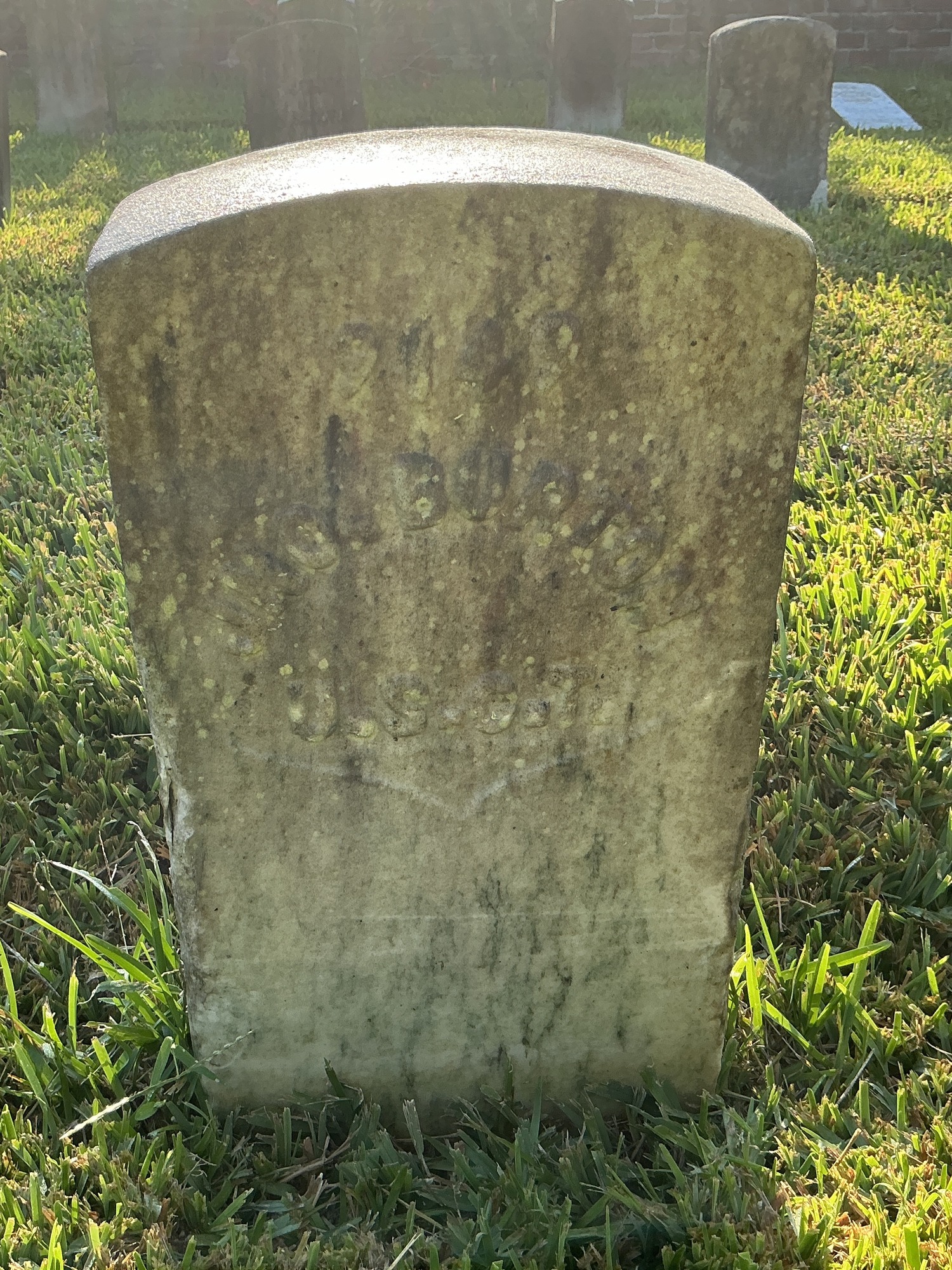 Front of historic upright marble headstone with recessed shield with recessed lettering face.