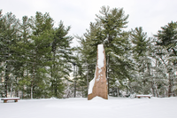 Granite monolith on a plaza surrounded by trees after a snowfall