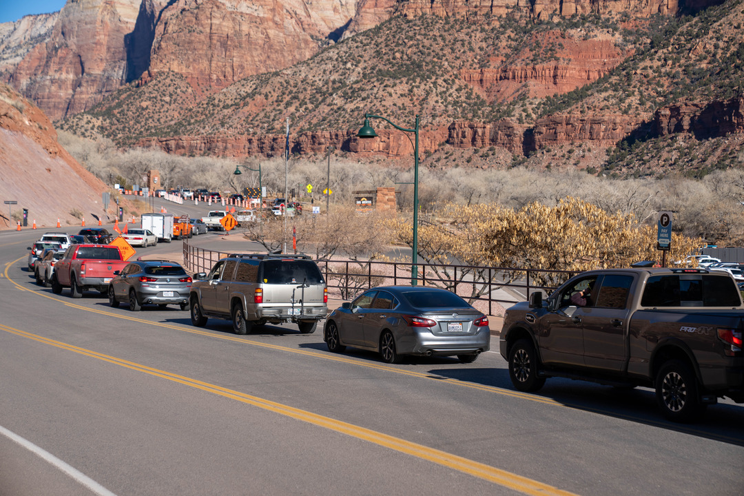 Vehicles on a paved road surrounded by red rocks of Zion Canyon