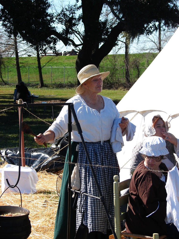 Women in period dress demonstrate campfire cooking during the Battle of New Orleans anniversary.