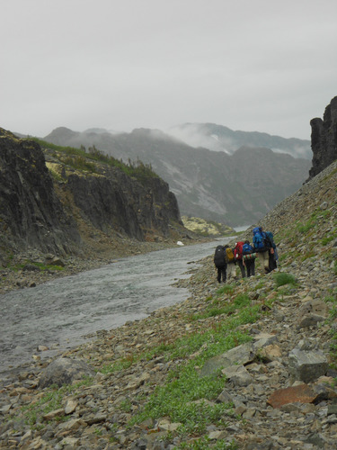 People walking in a rocky area along water