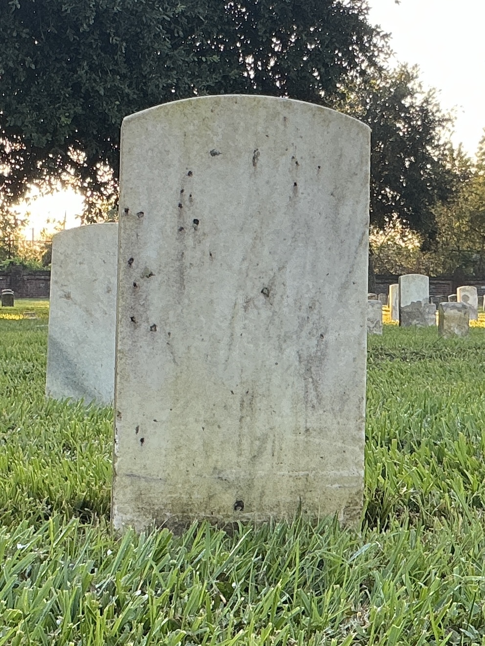 Back of historic upright marble headstone with recessed shield face.