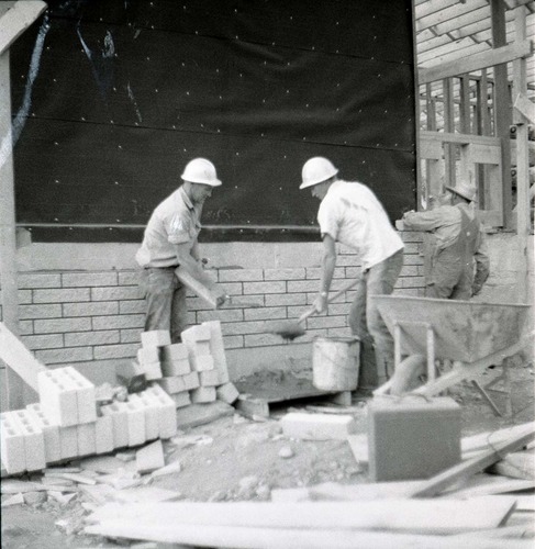 Three workers laying up the split blocks for the visitor center.