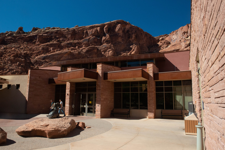 a brick building with large red rock cliffs above it