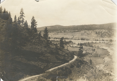 Sepia toned photograph of a road leading to a bridge over a river