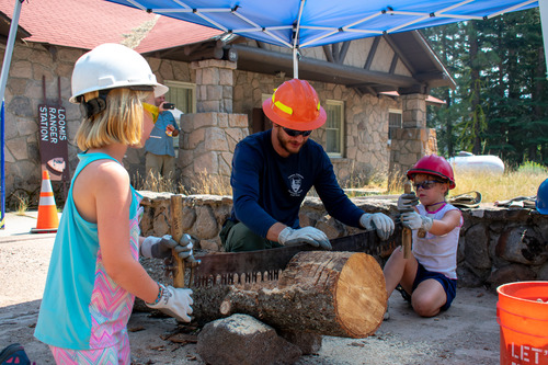 A boy stands next to his painting of B.F. Loomis photographing the Lassen Peak eruption at the 2018 Day in the Park event.