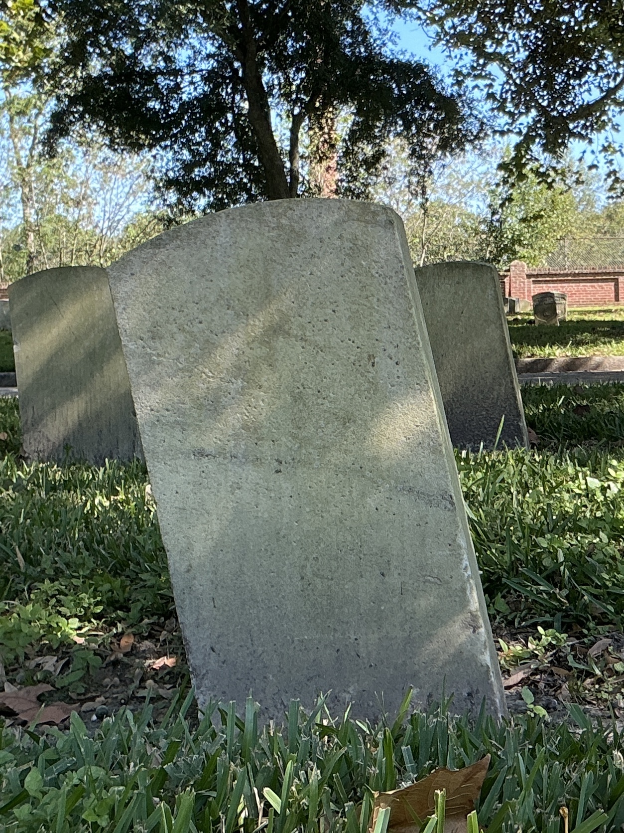 Back of historic upright marble headstone with recessed shield face.