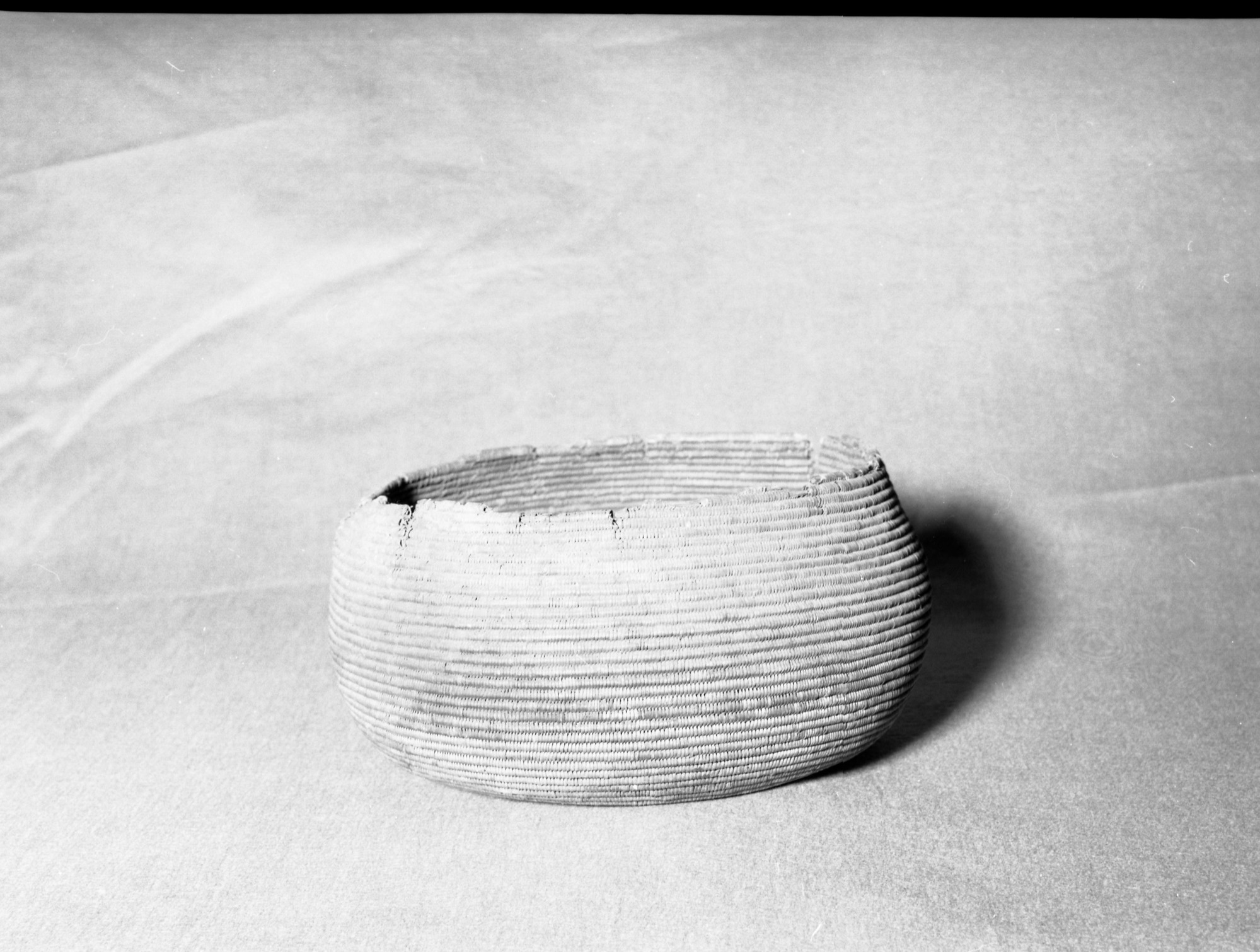 Mrs. Geraldine McConnell Collection. Object: Basket found in a cave at Knights Ferry, on the Stanislaus River. Excavated in the late 1960s. Dimensions: 10" x 5". Materials: Bulrush root pattern, sedge root, and scraped shoots. Technology: Split stitching, fag ends concealed in foundation, moving ends bound under. Notes: Basket is quite soiled and appears to have been buried in an ash deposit. Resembles a Patwin basket in design, technology and materials. Perhaps it was obtained in trade by native residents of Knights Ferry. Photographed by Michael Dixon in January 1983. Catalogued by Craig Bates and Barbara Beroza. Yosemite Collections, National Park Service.