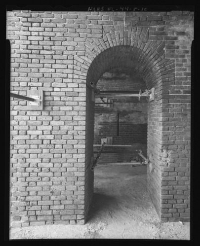 Black and white photograph of deep brick archway and metal supports