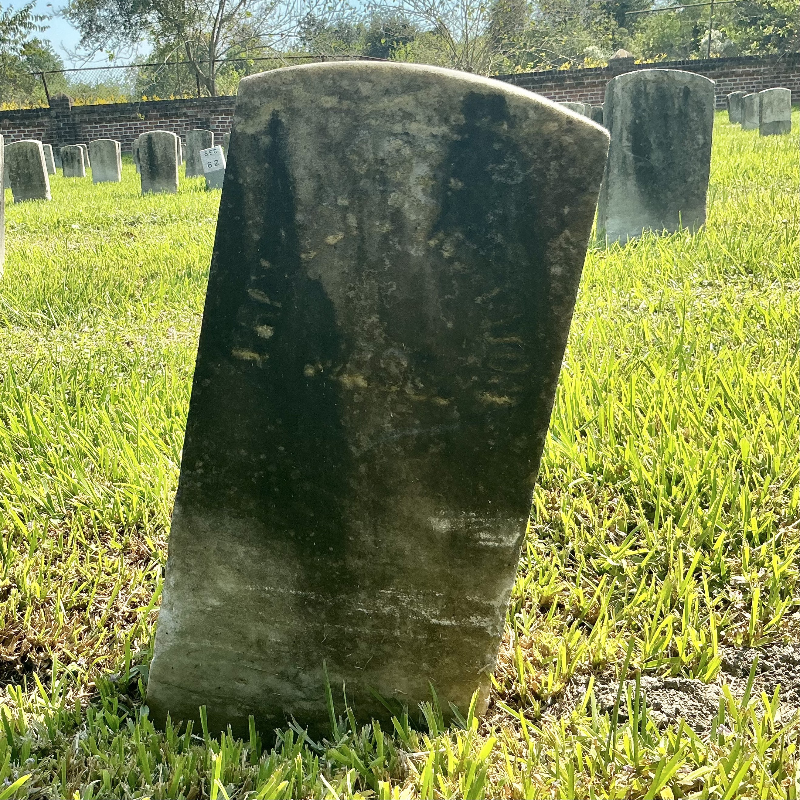 Front of historic upright marble headstone with recessed shield face.