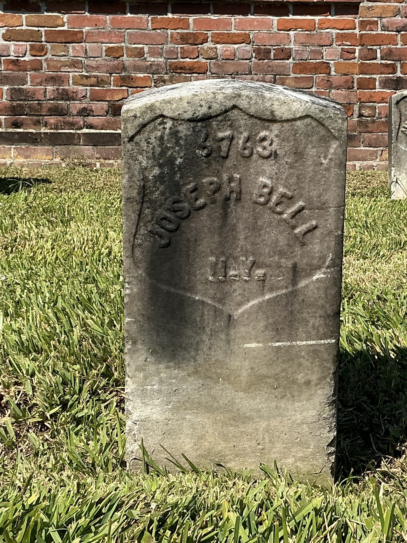 Front of historic upright marble headstone with recessed shield face.