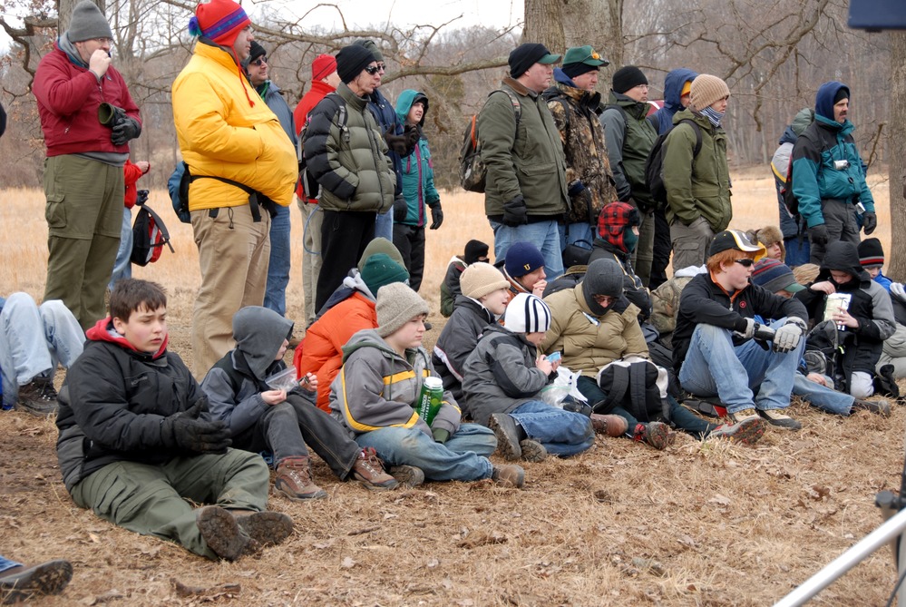 Scouts sit and listen to a program about soldiers and their equipment.