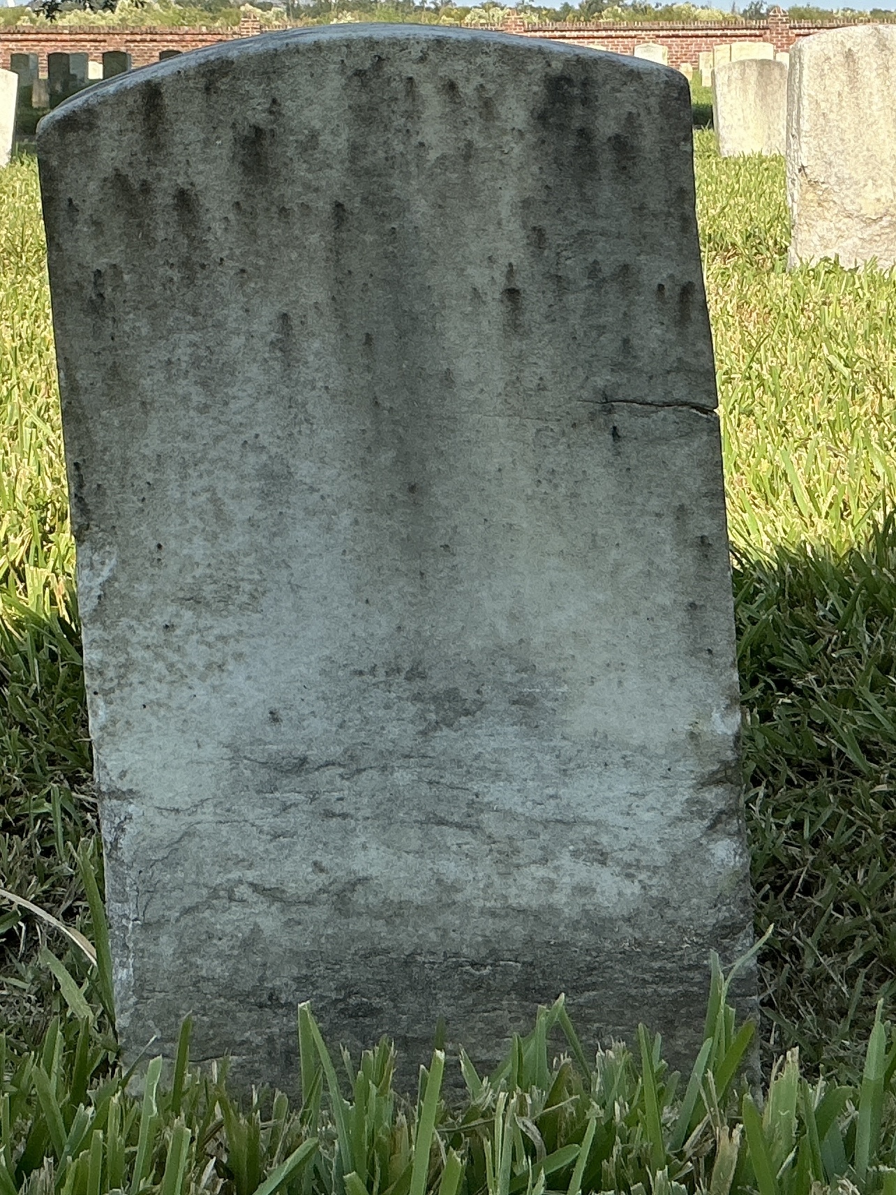 Back of historic upright marble headstone with recessed shield face.