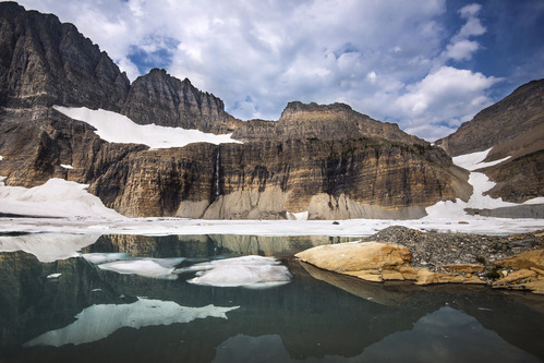 Mountain ridge with glacier snow and ice above teal lake