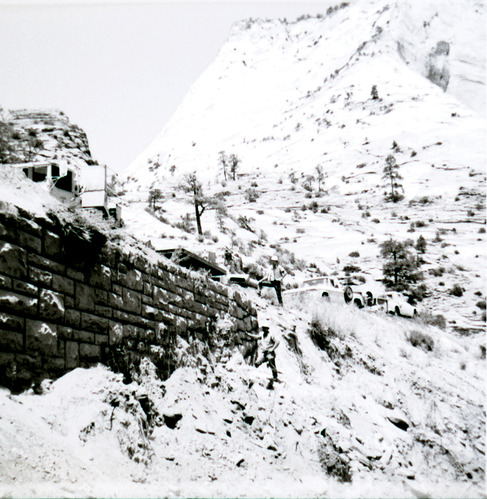 Retaining wall along East Rim road in need of repairs with line of construction vehicles.