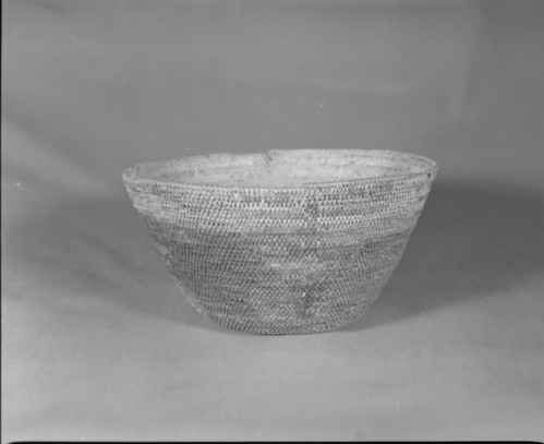 Private Collection. Object: Miwok basket. Dimensions: 10 1/2 x 5 1/2". Materials: Split bull pine and redbud. Technology: Single rod, interlocking stitch, fag ends trimmed on workface, moving ends trimmed on interior and some bound under. Original rim missing. Five vertical design units of stacked inverted tree like forms. Encrustation, probably from acorn. Collection History: Purchased from Maggie Longfellow's mother, also known as Mrs. Longfellow Poncho. Photographed by Michael Dixon. Catalogued by Craig Bates and Barbara Beroza. Yosemite Collections, National Park Service.