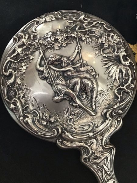 a woman and child are sitting on swing together and this is on the back of a handheld mirror