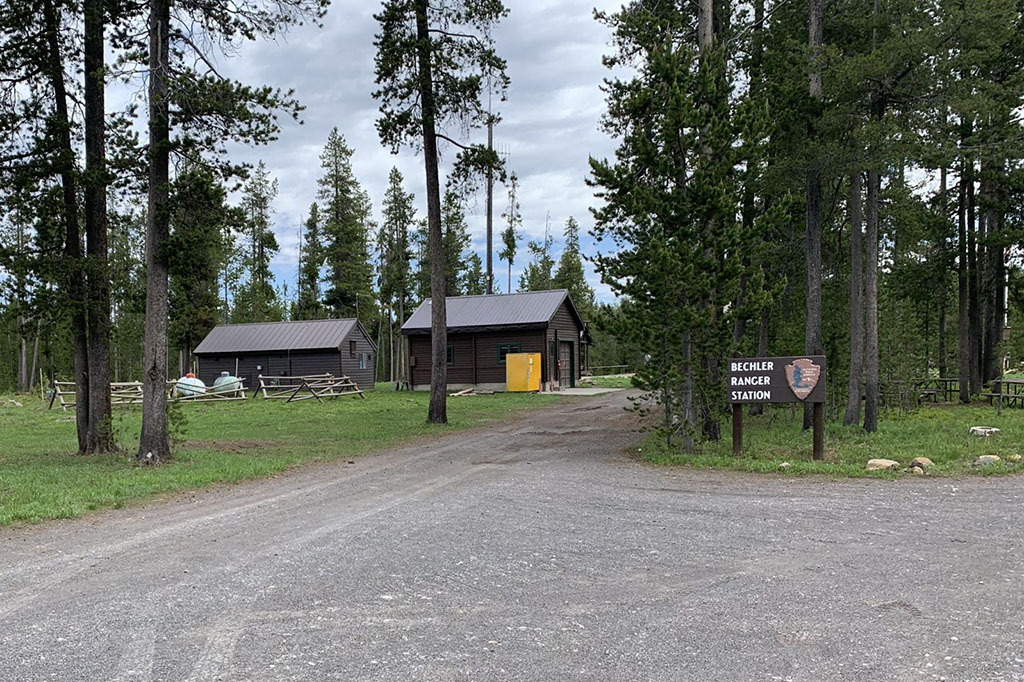 Two small cabins near a wooden sign that reads 'bechler ranger station.'