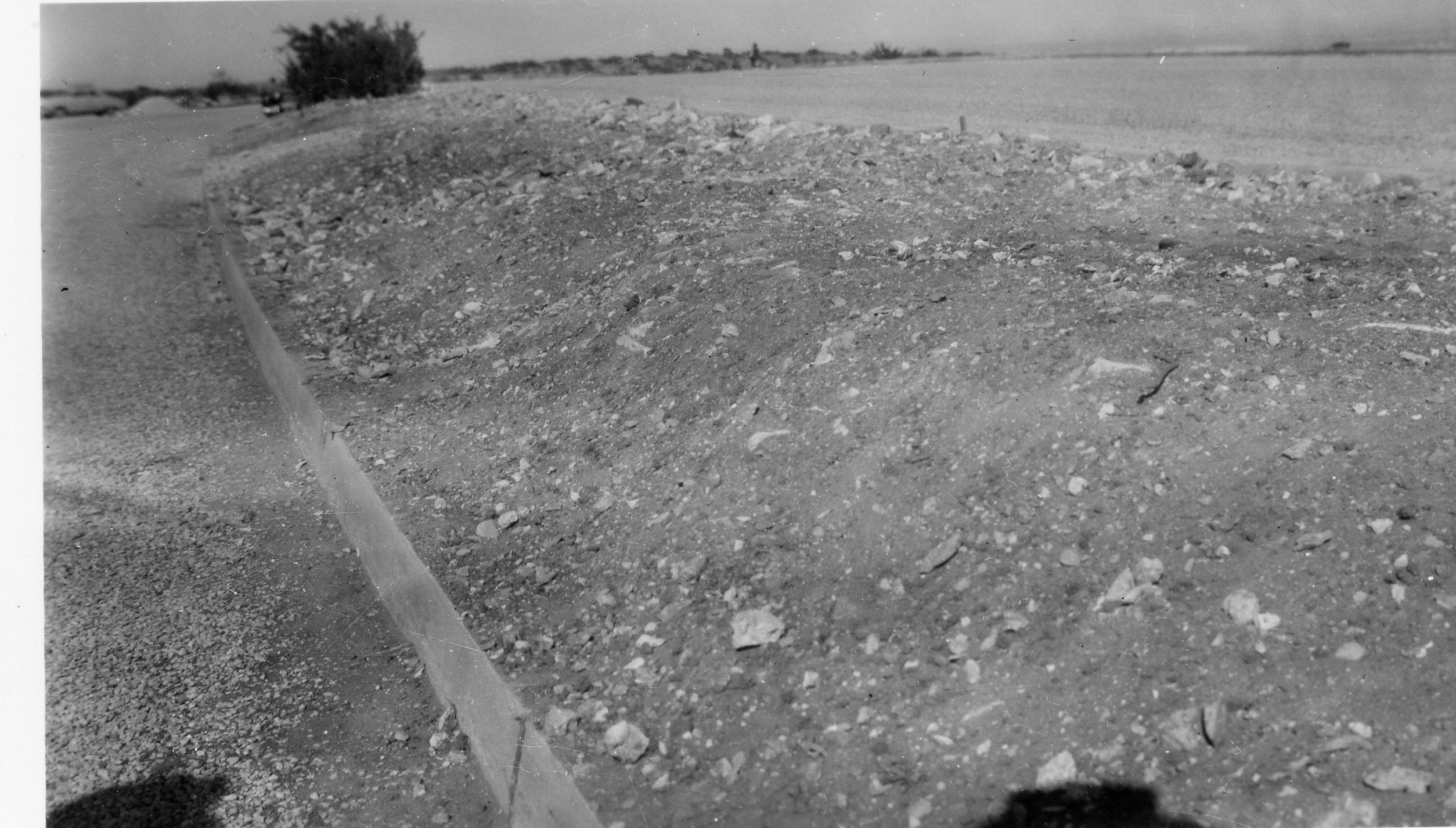 A black and white photograph of a dirt mound in the middle of the parking lot.