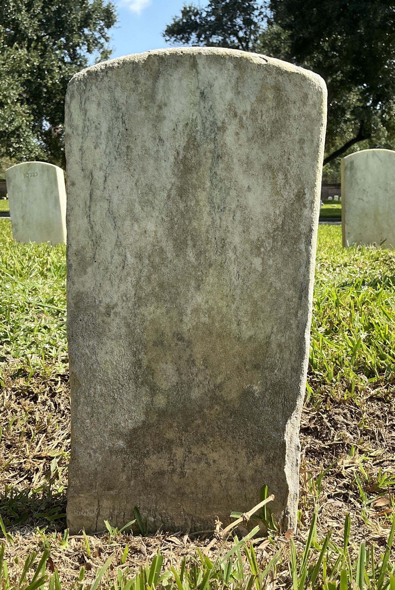 Back of historic upright marble headstone with recessed shield face.