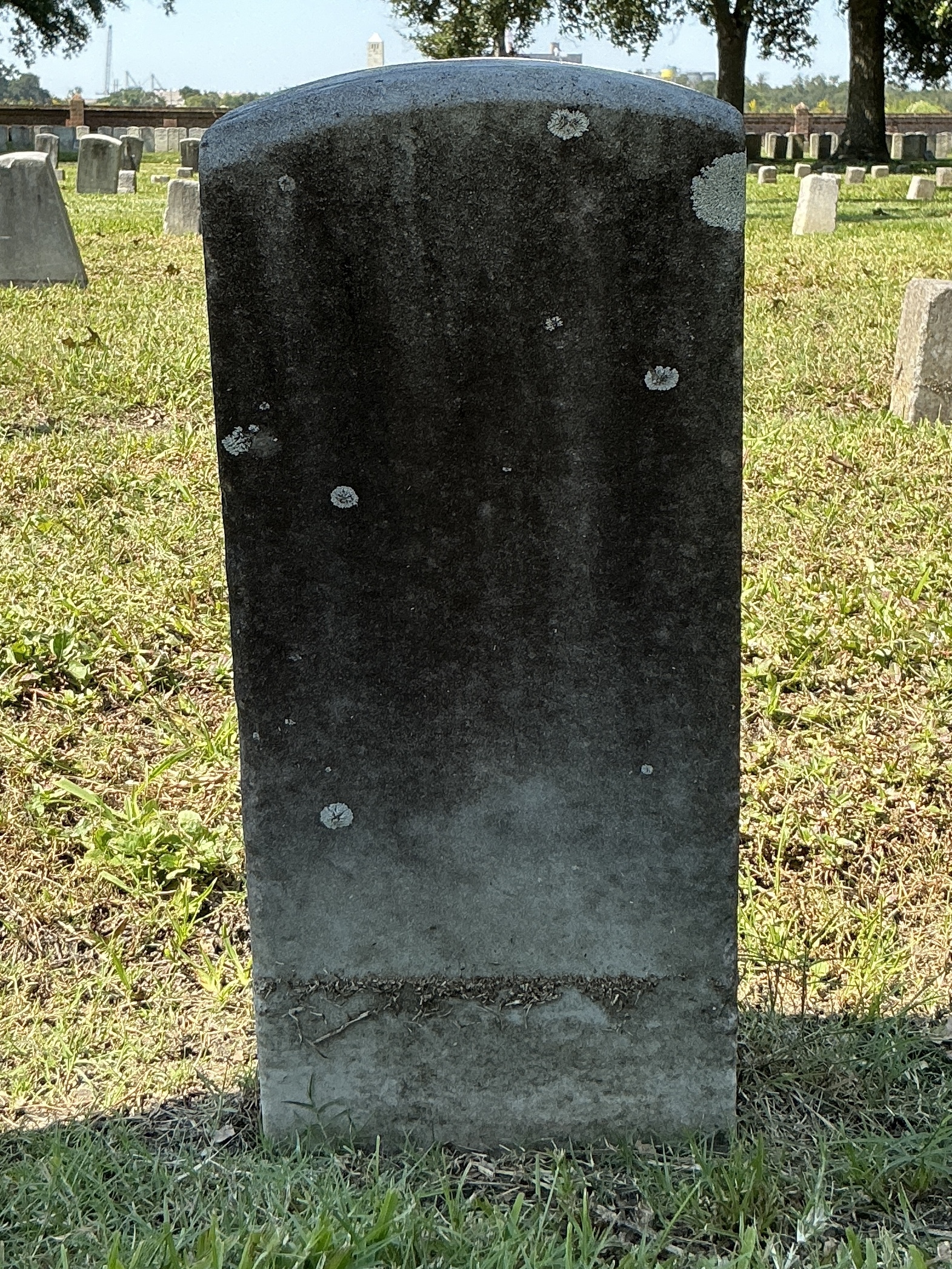 Back of historic upright marble headstone with recessed shield face.