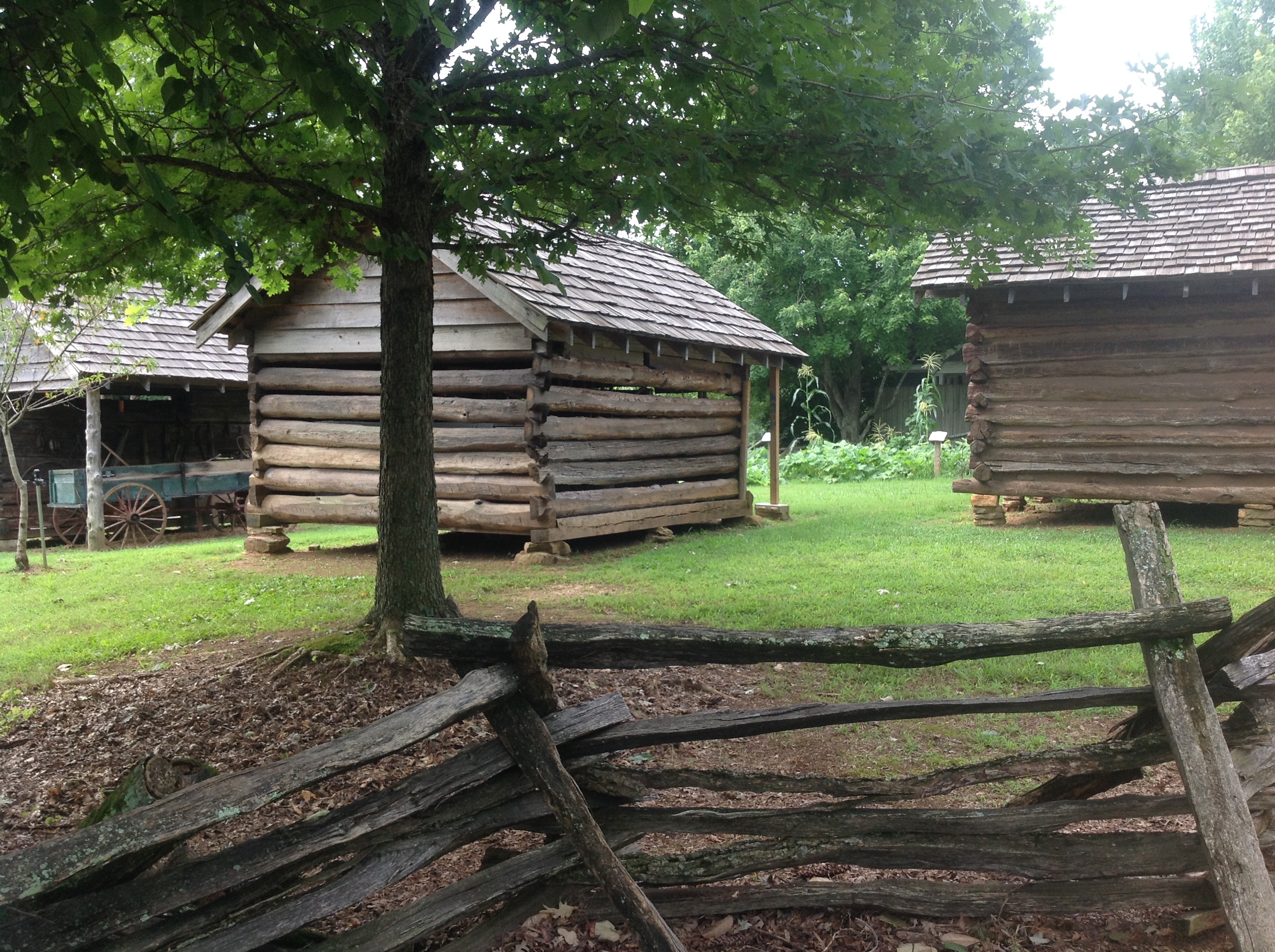Two log cabins next to a fence.