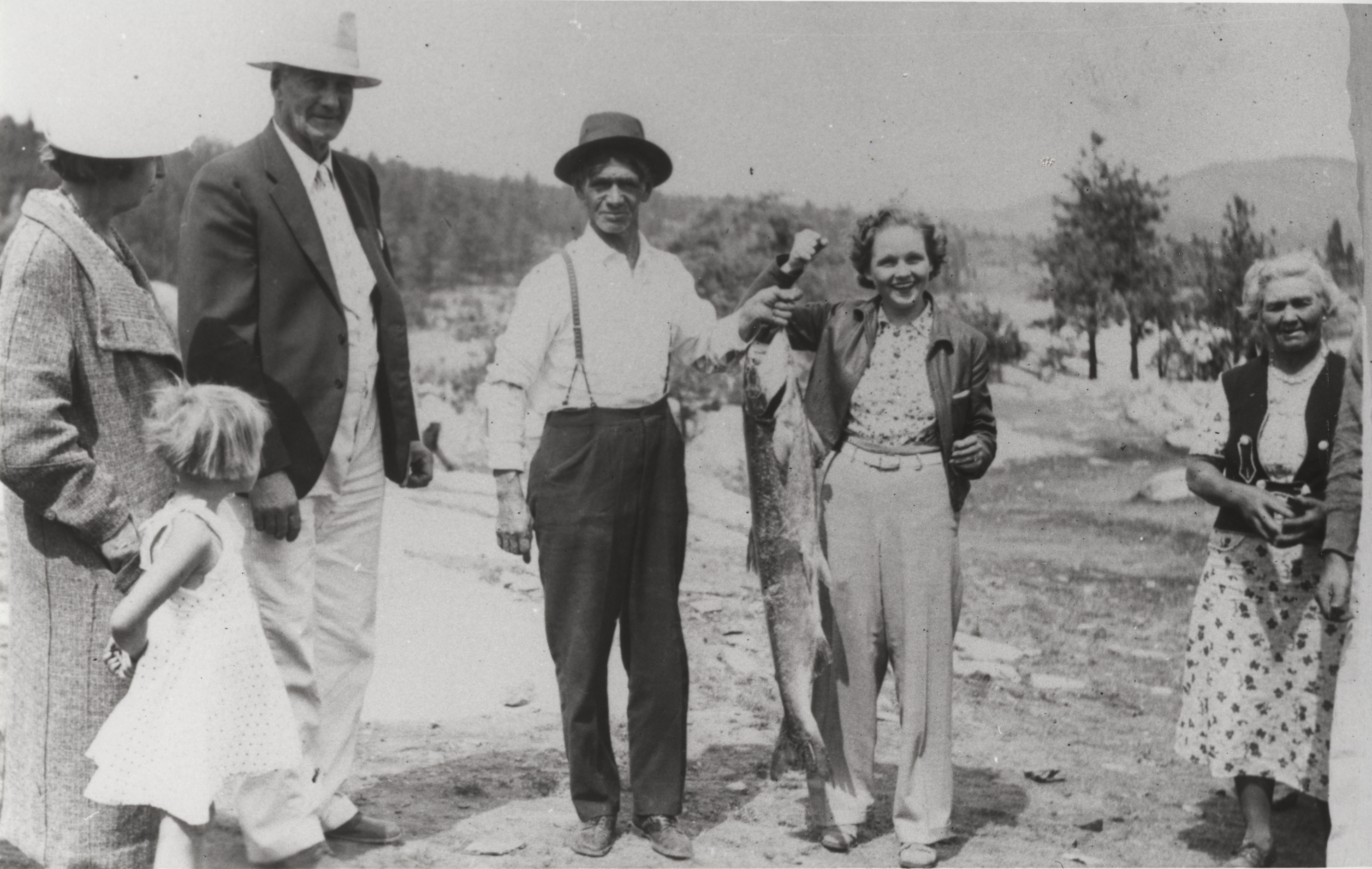 Black and white photograph of a man and woman holding a large fish between them 