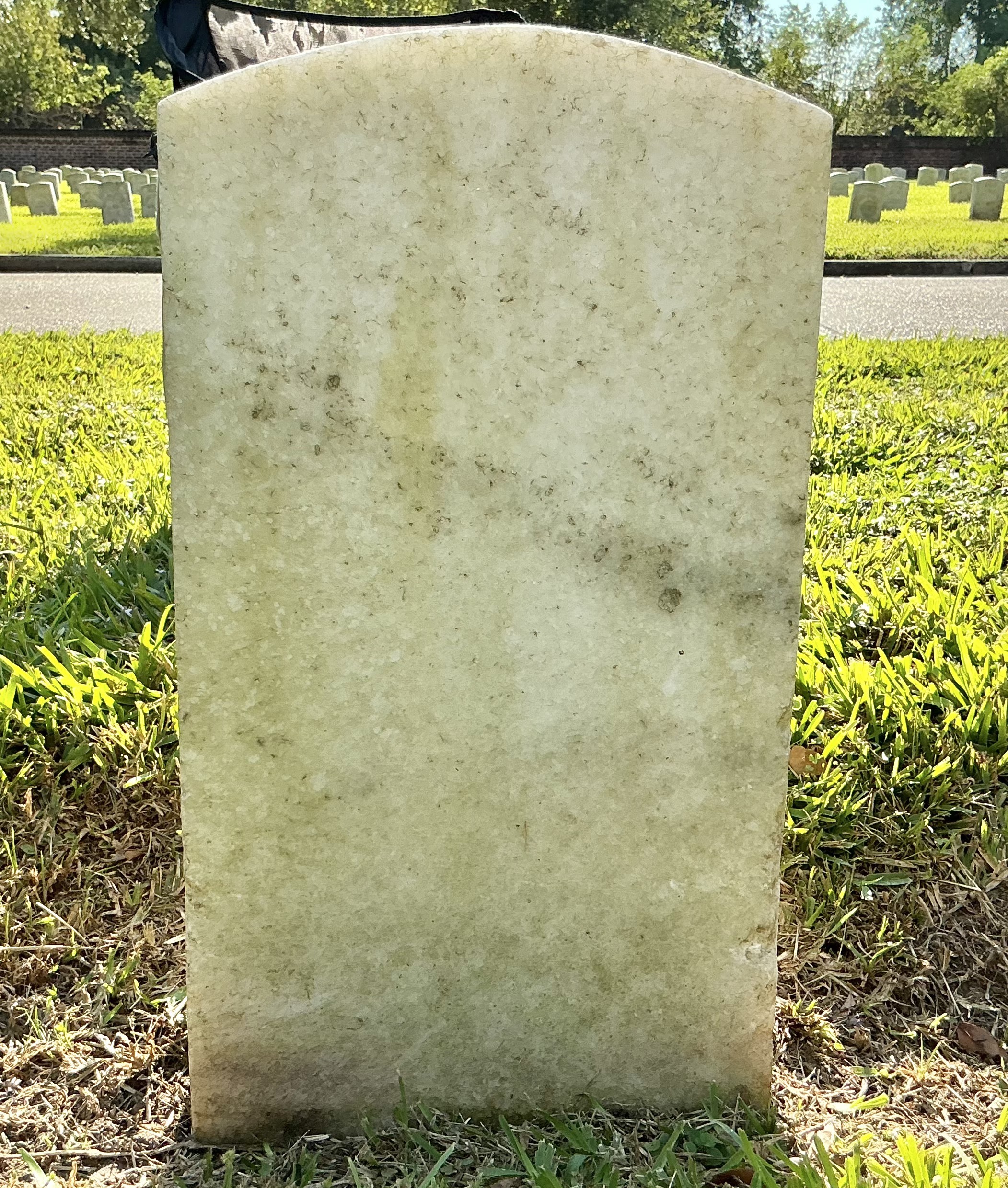 Back of historic upright marble headstone with recessed shield face.