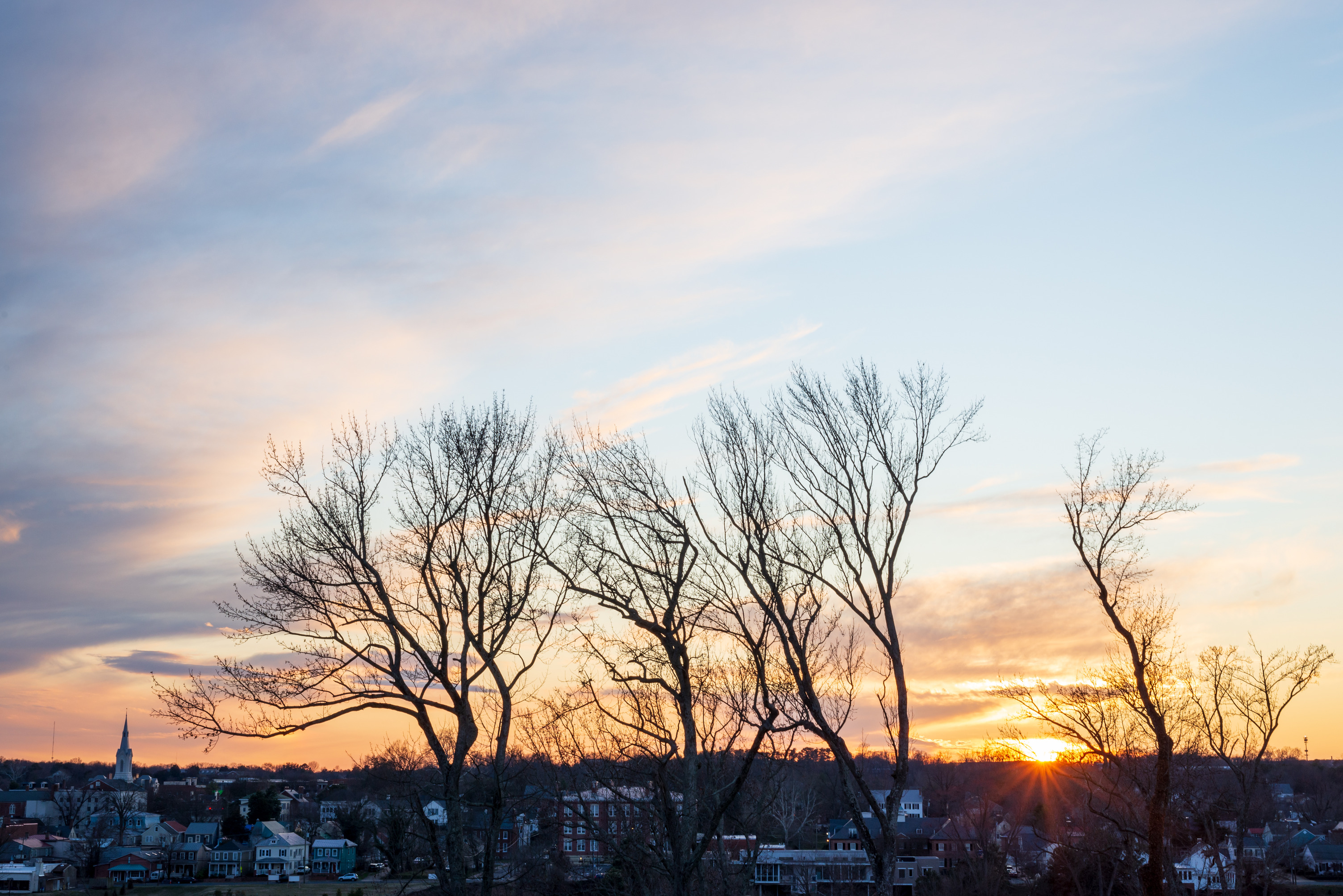 A sunset view with a city across from a river.
