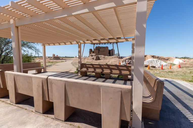 Four long benches covered by a shade structure. 