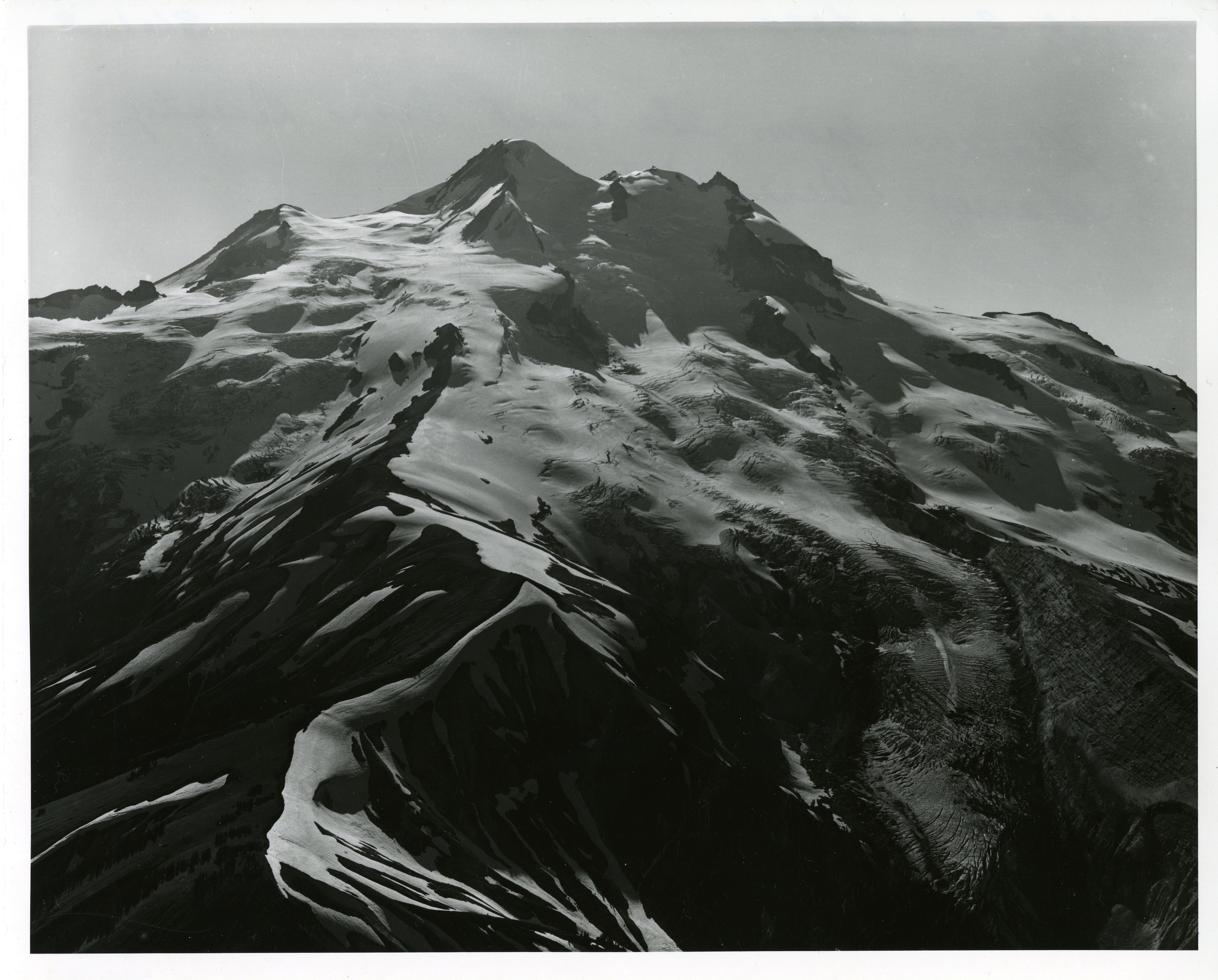 A rocky, glaciated mountain peak. Snow and ice covers most of the surface.