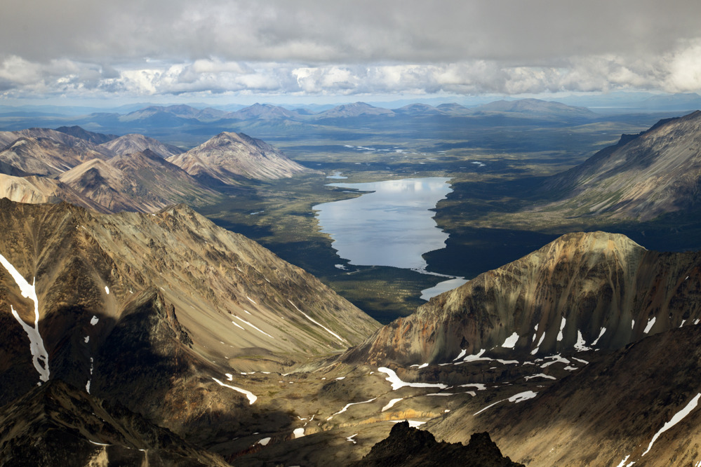 An aerial view of Lower Twin Lake nestled behind the rust colored Neacola Mountains