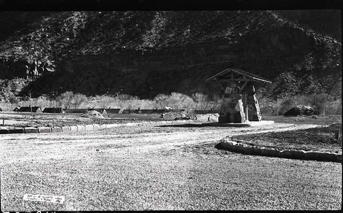 Utah Parks Company (Union Pacific Railroad) gas pump at Camp Center, (at South Campground, South Entrance, Civilian Conservation Corps (CCC) buildings in the distance.
