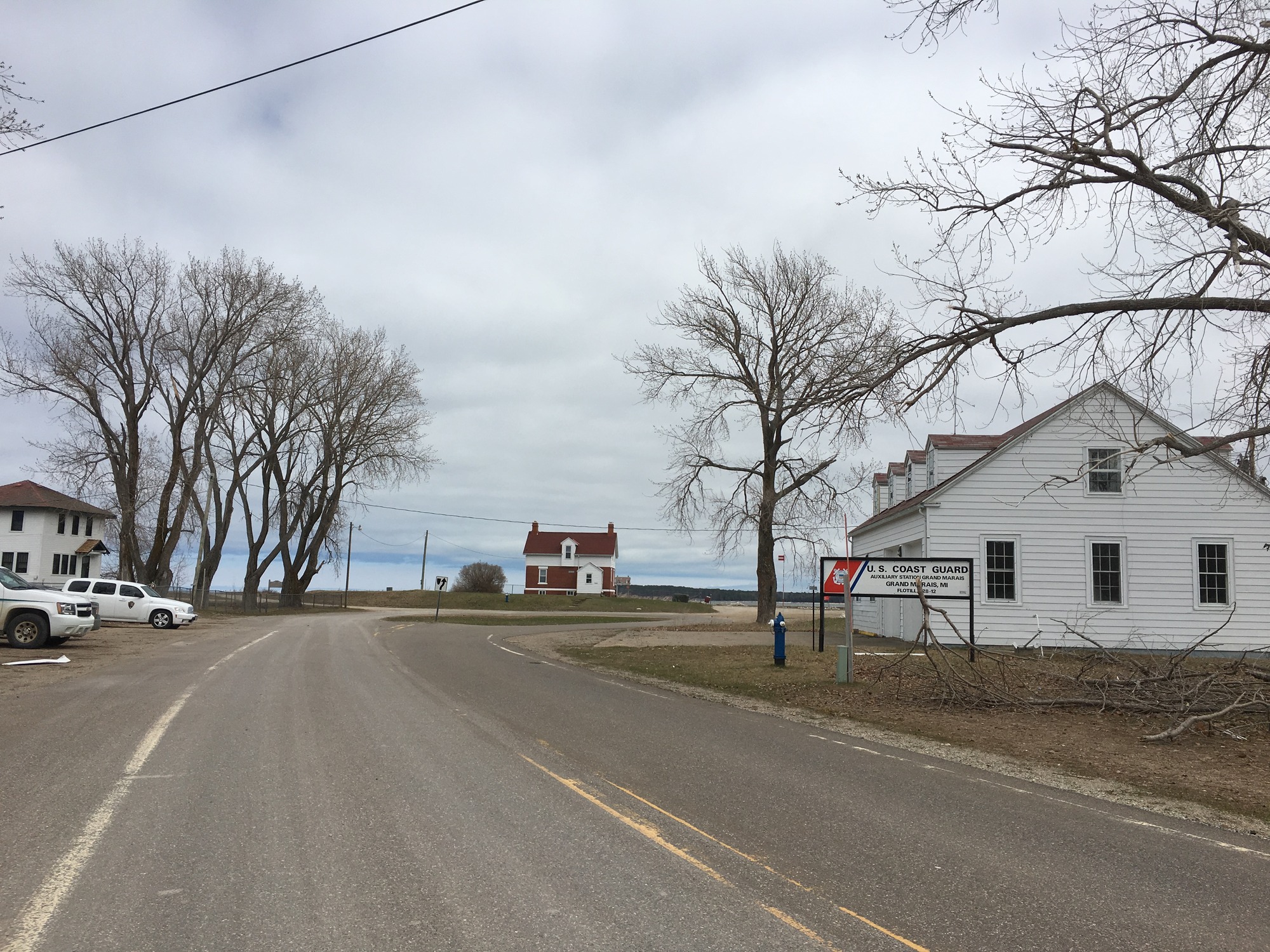 road with US Coast Guard sign by two story white building. Two other two story buildings are in the distance.