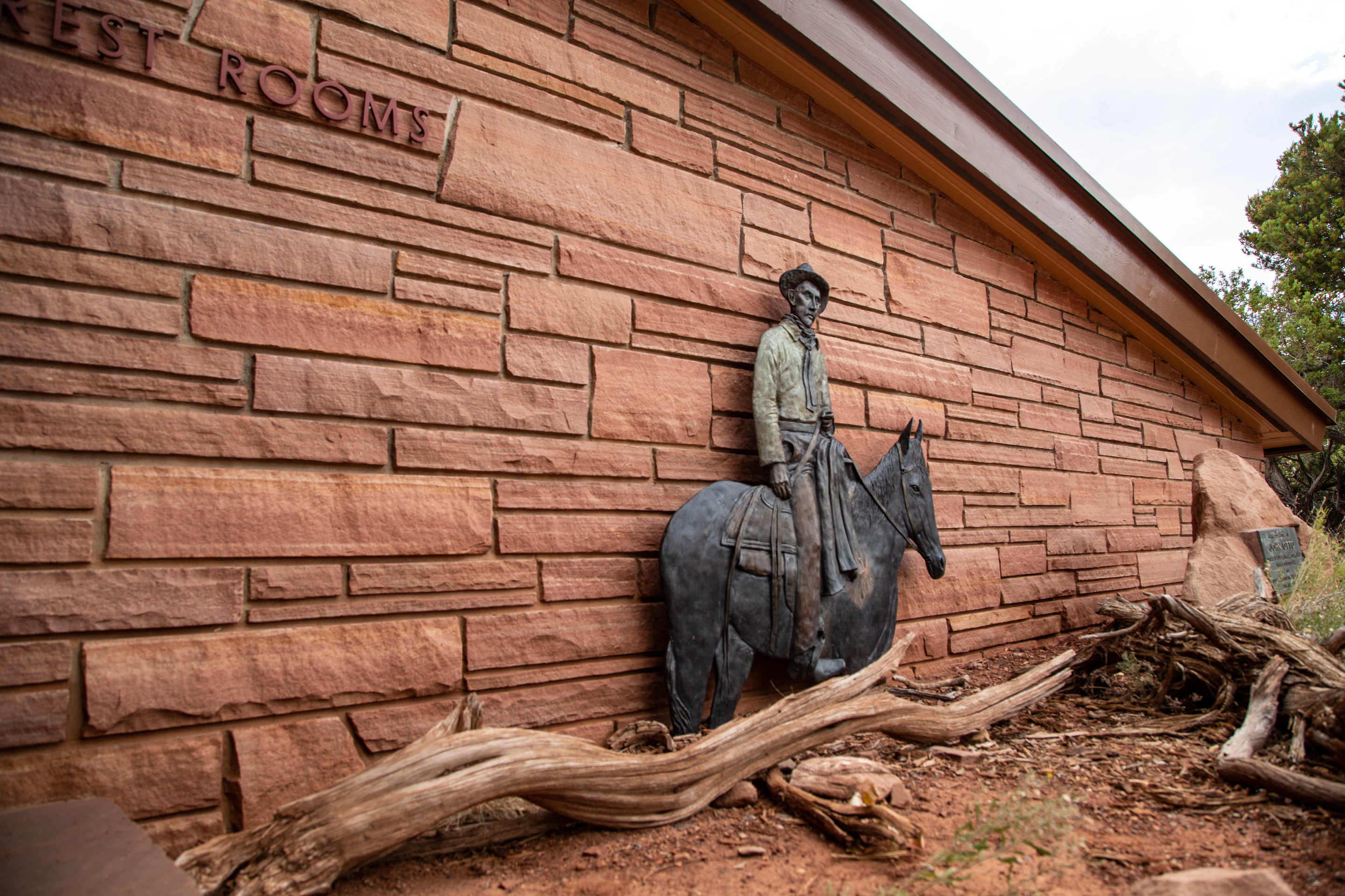 Flat, metal statue of John Otto on horseback standing against the visitor center wall