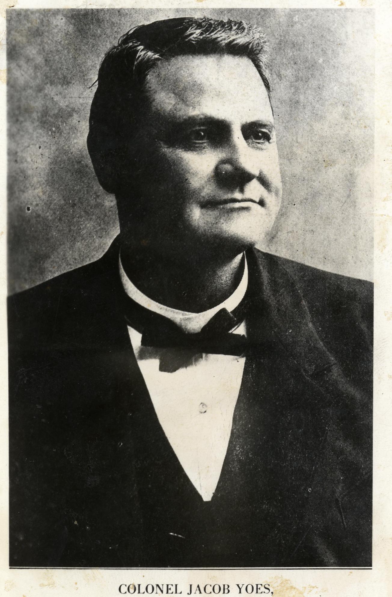 A white man with short hair wearing a dark colored suit