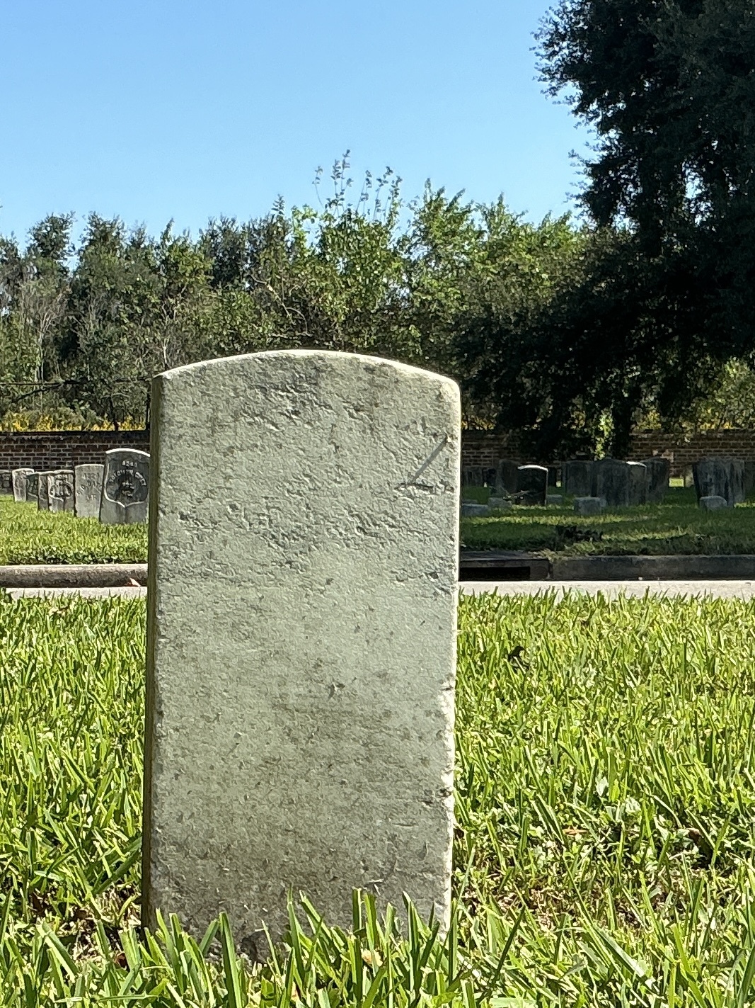 Back of historic upright marble headstone with recessed shield face.