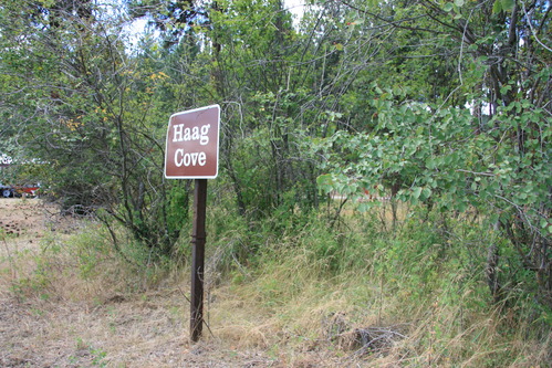 Color photograph of a brown sign in front of bushes