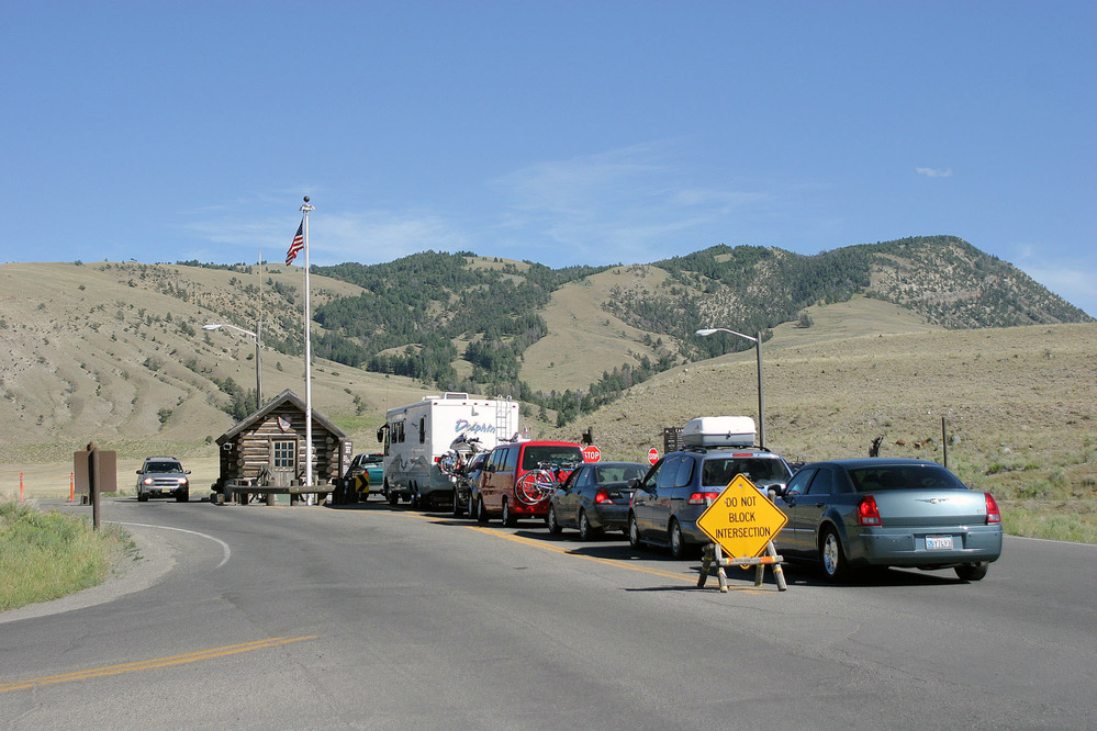 Seven cars lined up at entrance station with Mt. Everts in background