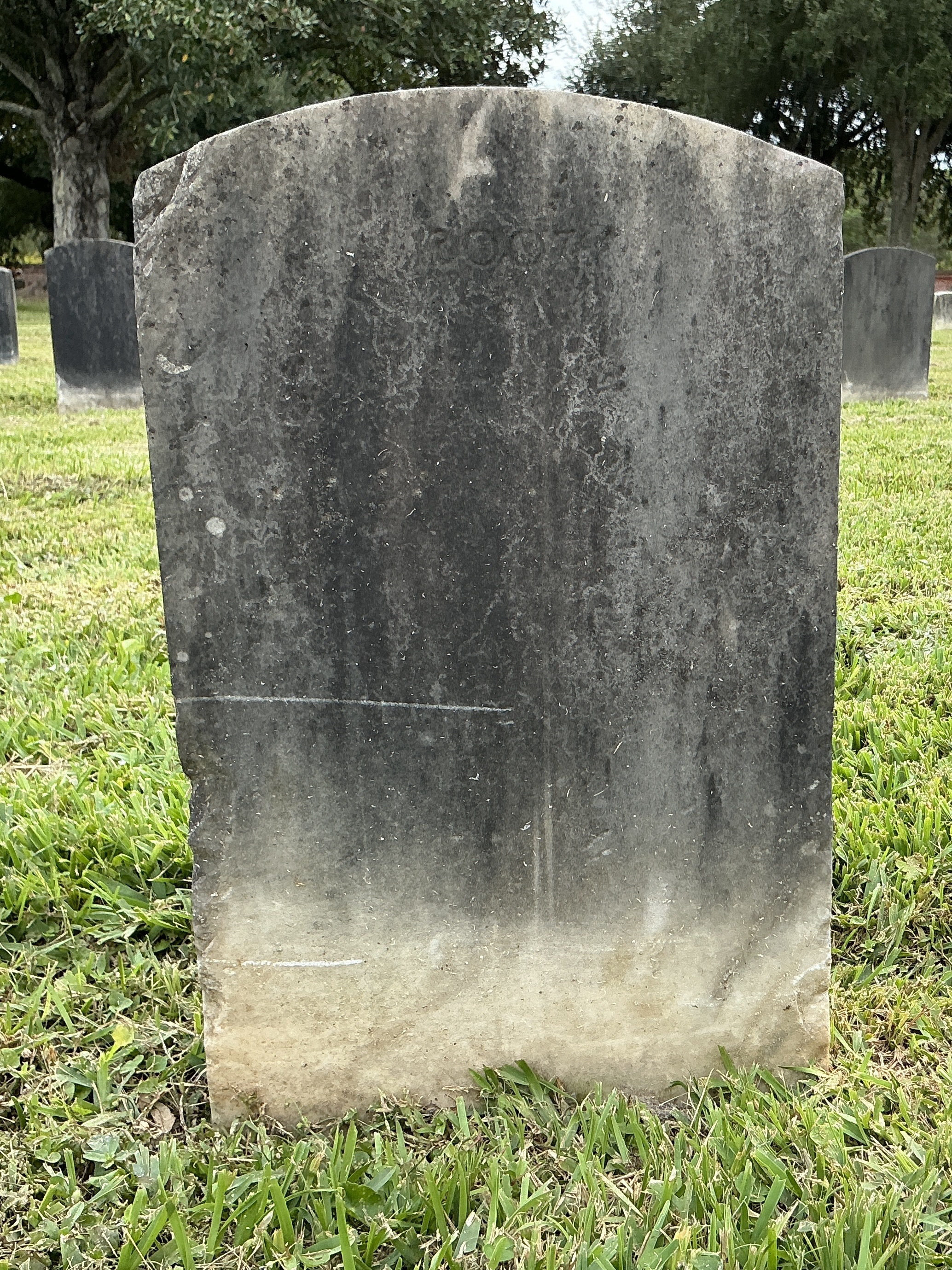 Back of upright marble headstone with flat face.