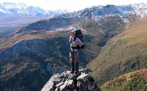 hiker standing on a rocky outcropping overlooking mountains and valleys