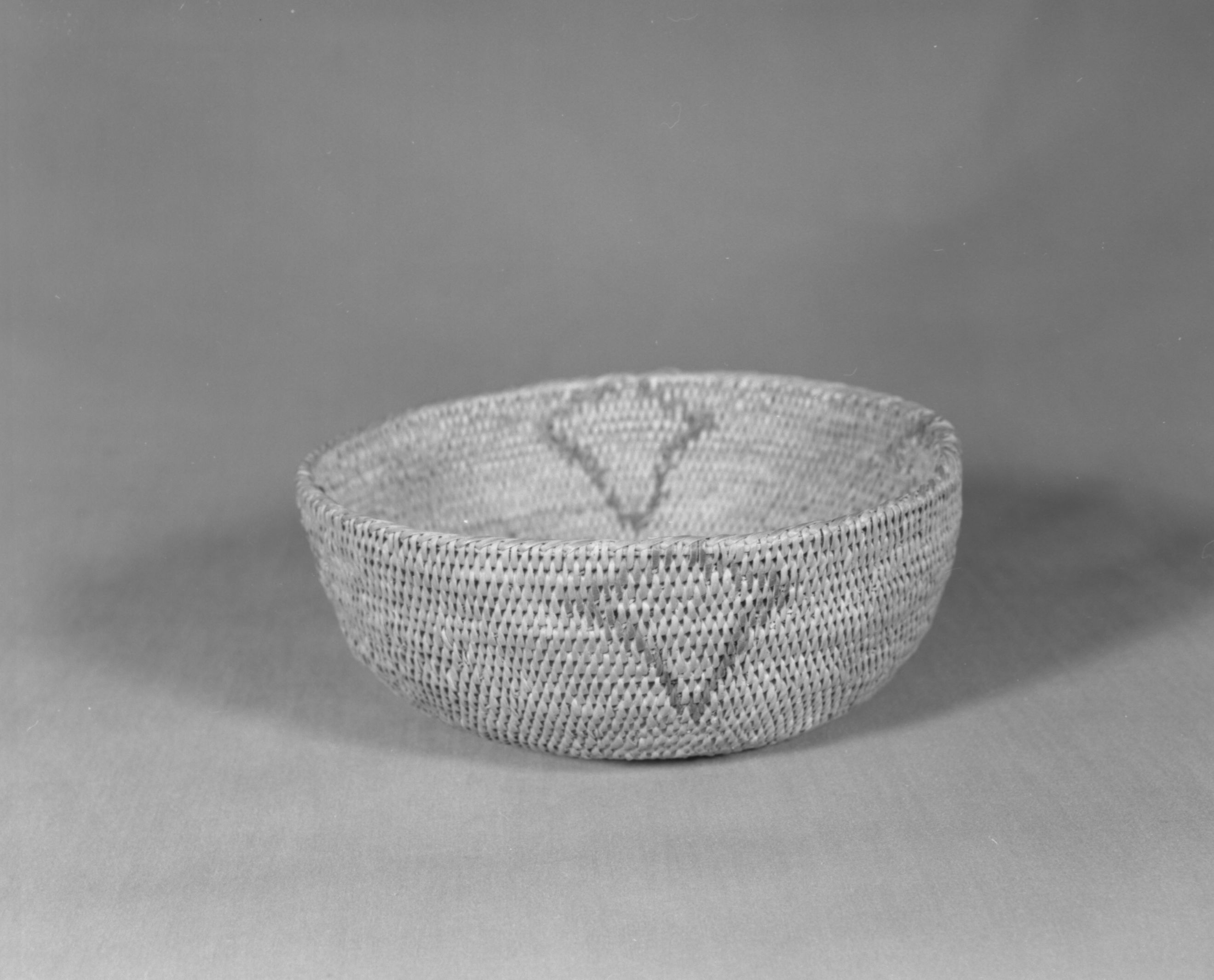 Private Collection. Object: Miwok basket. Dimensions: 7 1/2 x 3 1/4". Materials: Bull pine, redbud, & fern root. Technology: Single rod, fag ends trimmed on work face, moving ends trimmed on interior. Leftward coil direction, rim overstitched. Lower part of design in fern root and upper part in redbud. Overstitched clockspring. Collection History: Made by Matilda, a Sonora Miwok, c. 1920. Photographed by Michael Dixon. Catalogued by Craig Bates and Barbara Beroza. Yosemite Collections, National Park Service.