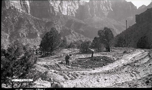 Excavation for water tank with laborers digging in cleared ground.