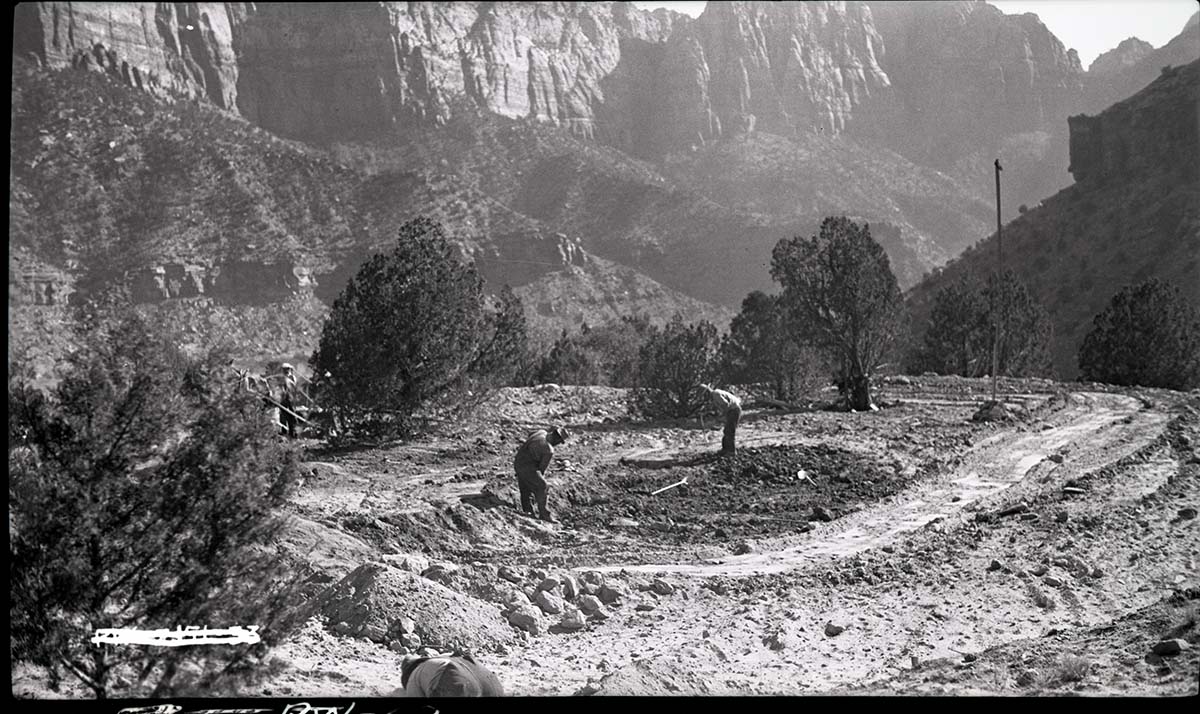 Excavation for water tank with laborers digging in cleared ground.