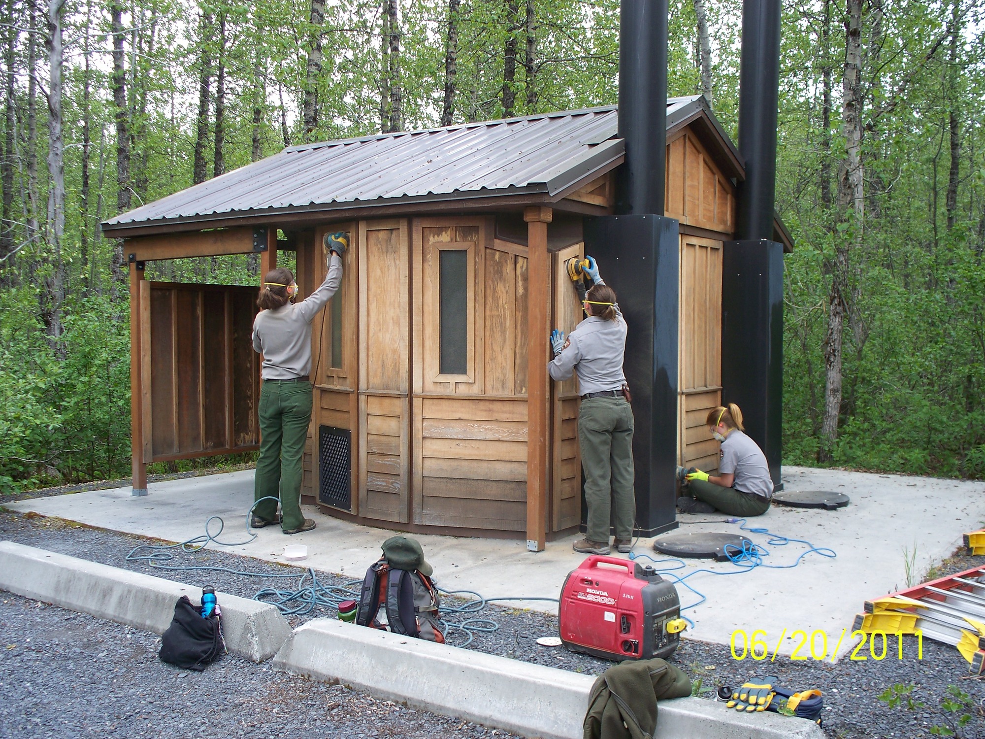 Maintenance workers sanding down the Vault Toilets at Exit Glacier