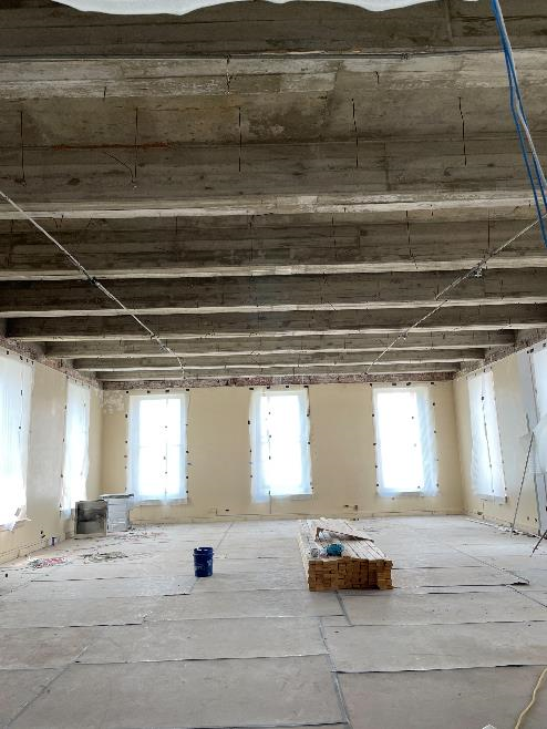 A room in the Old Courthouse with may windows on 3 sides. The ceiling is exposed and reveals the poured concrete slabs and beams above.