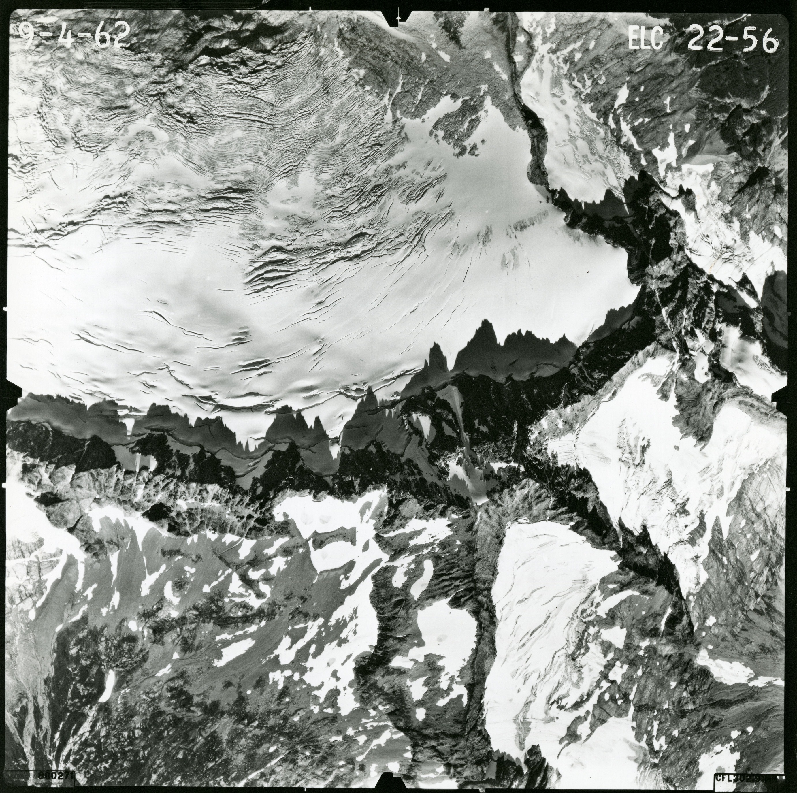 Black and white aerial photograph of glaciated mountain peaks and valleys.