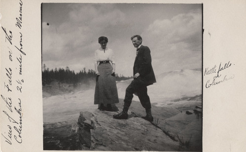 Black and white photograph, with a wide border and handwritten caption, of a man and woman standing by a waterfall