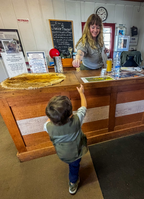 A ranger hands a junior ranger badge to a child over a front desk. 