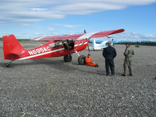 plane and two people on a gravel surface